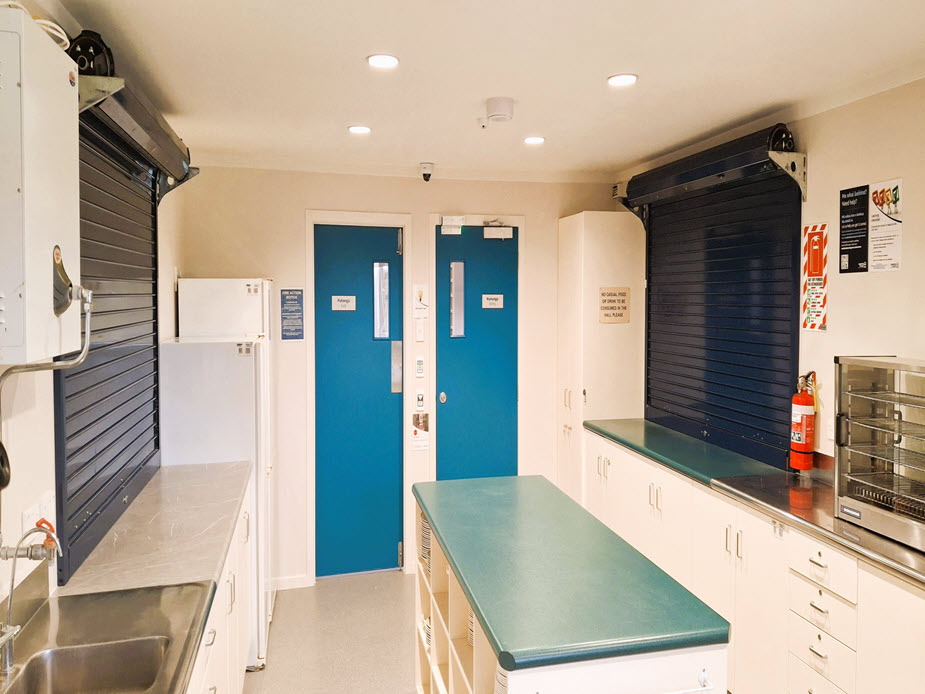 Utility kitchen with servery shutters, blue doors, and stainless-steel bench