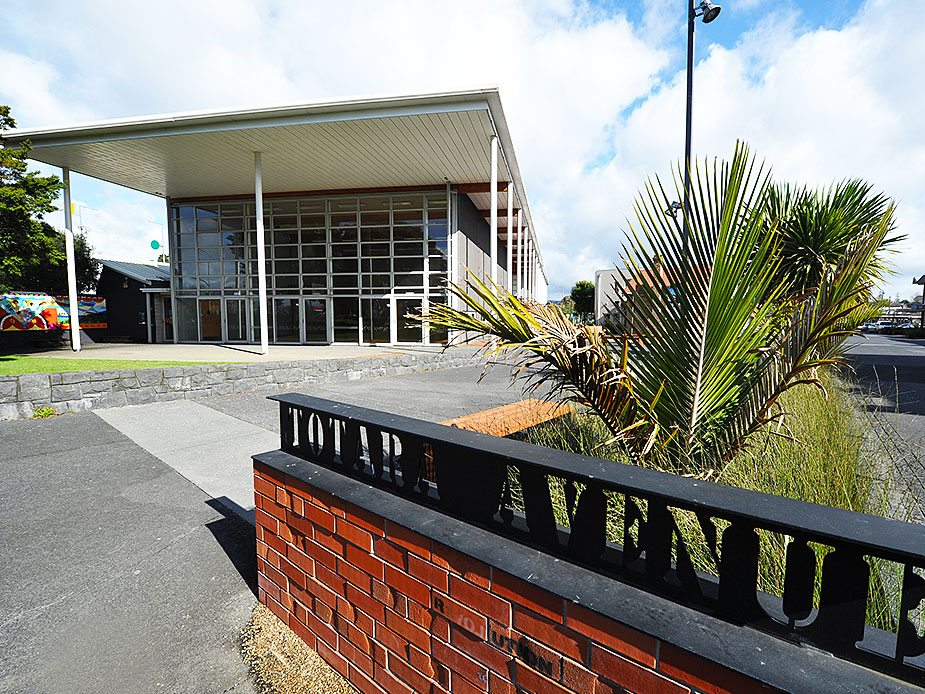 Mid-century community centre exterior with flat canopy roof and floor-to-ceiling glazing