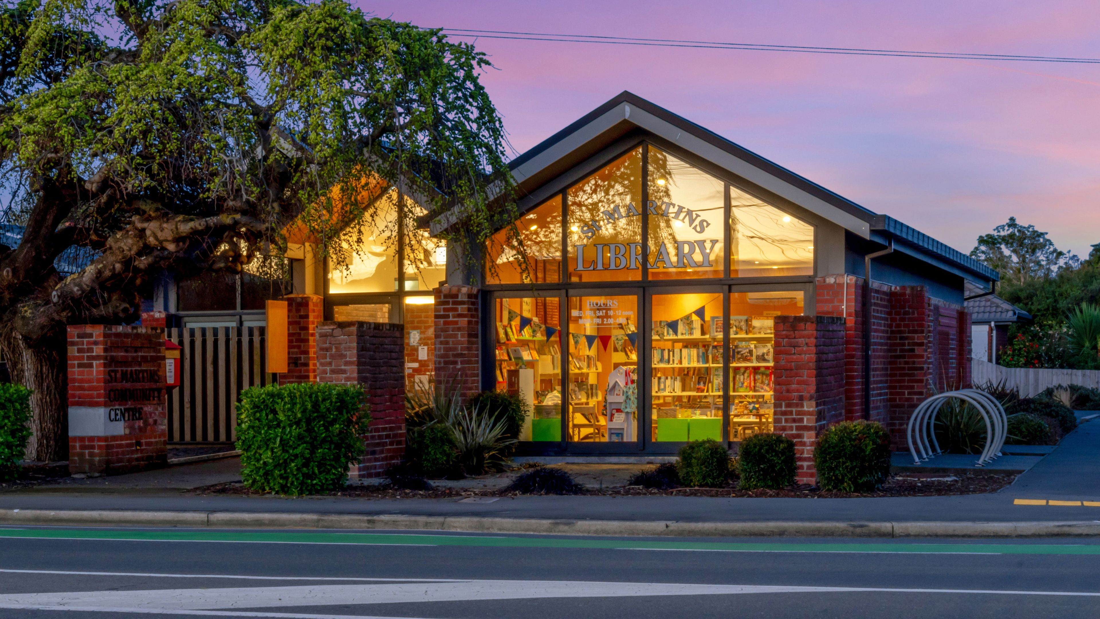 Brick community centre library building lit up at dusk