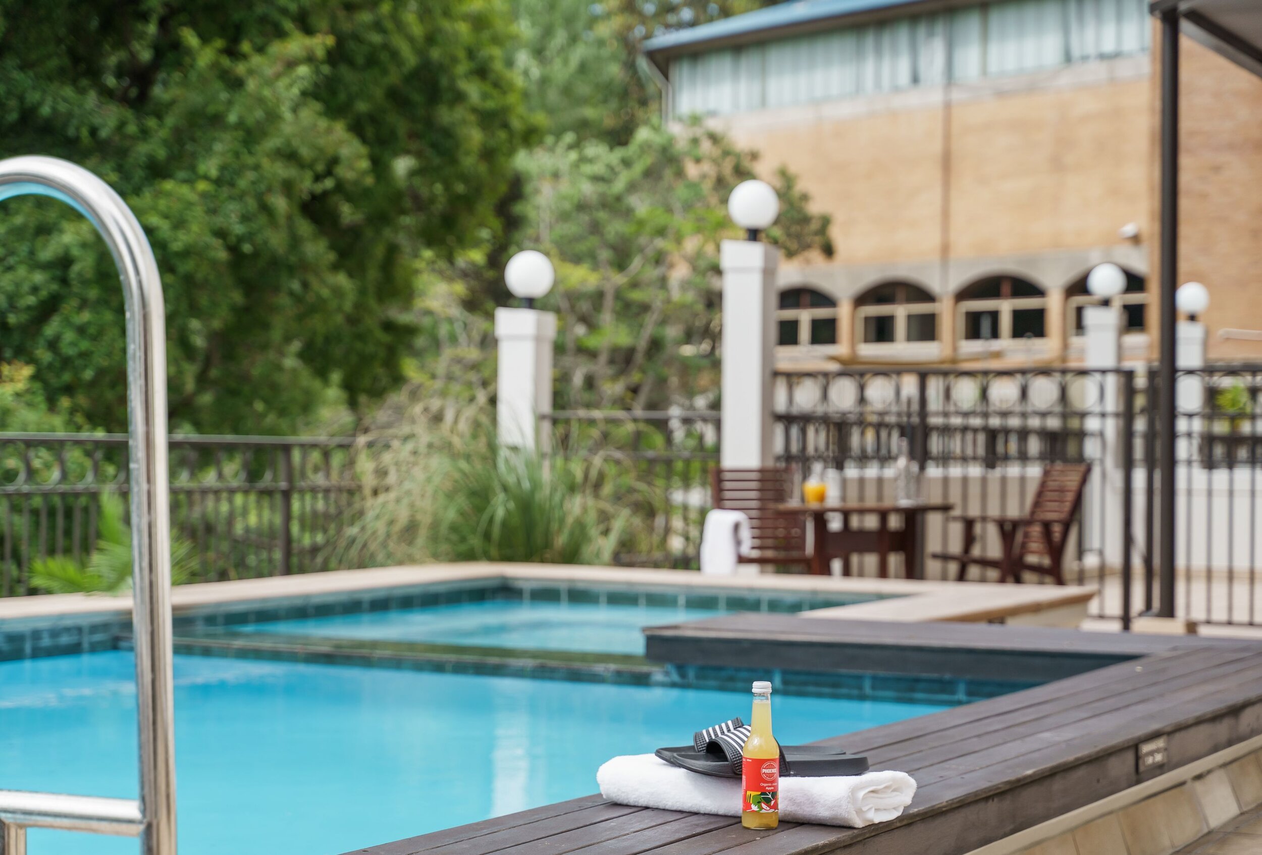 Outdoor tiled pool with timber deck, iron balustrade and multi-storey building behind