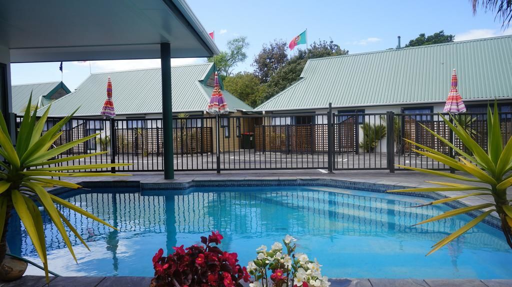 Outdoor pool area with umbrellas and low-set buildings behind