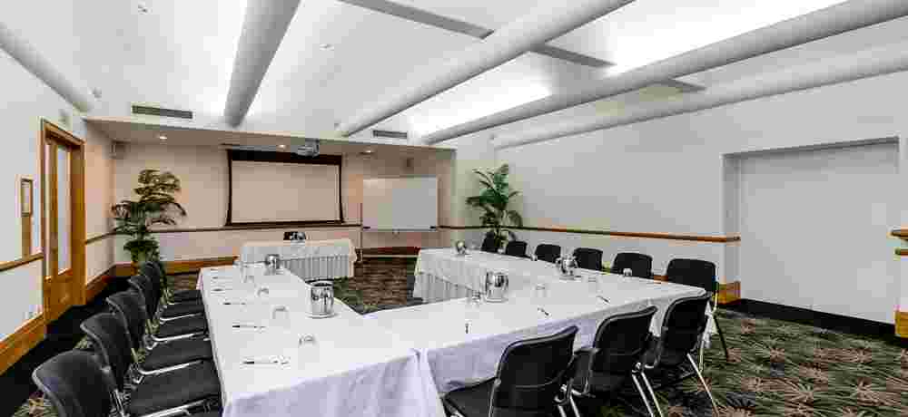 Conference room with U-shaped table, projection screen and plants
