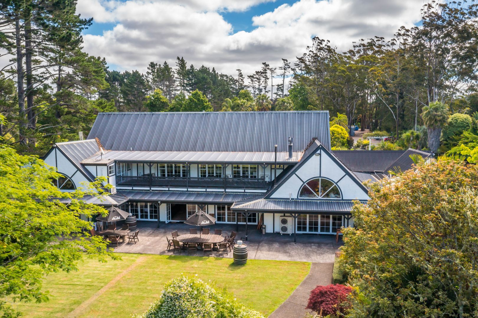 Lodge building with steeply pitched roof set among trees with outdoor dining area