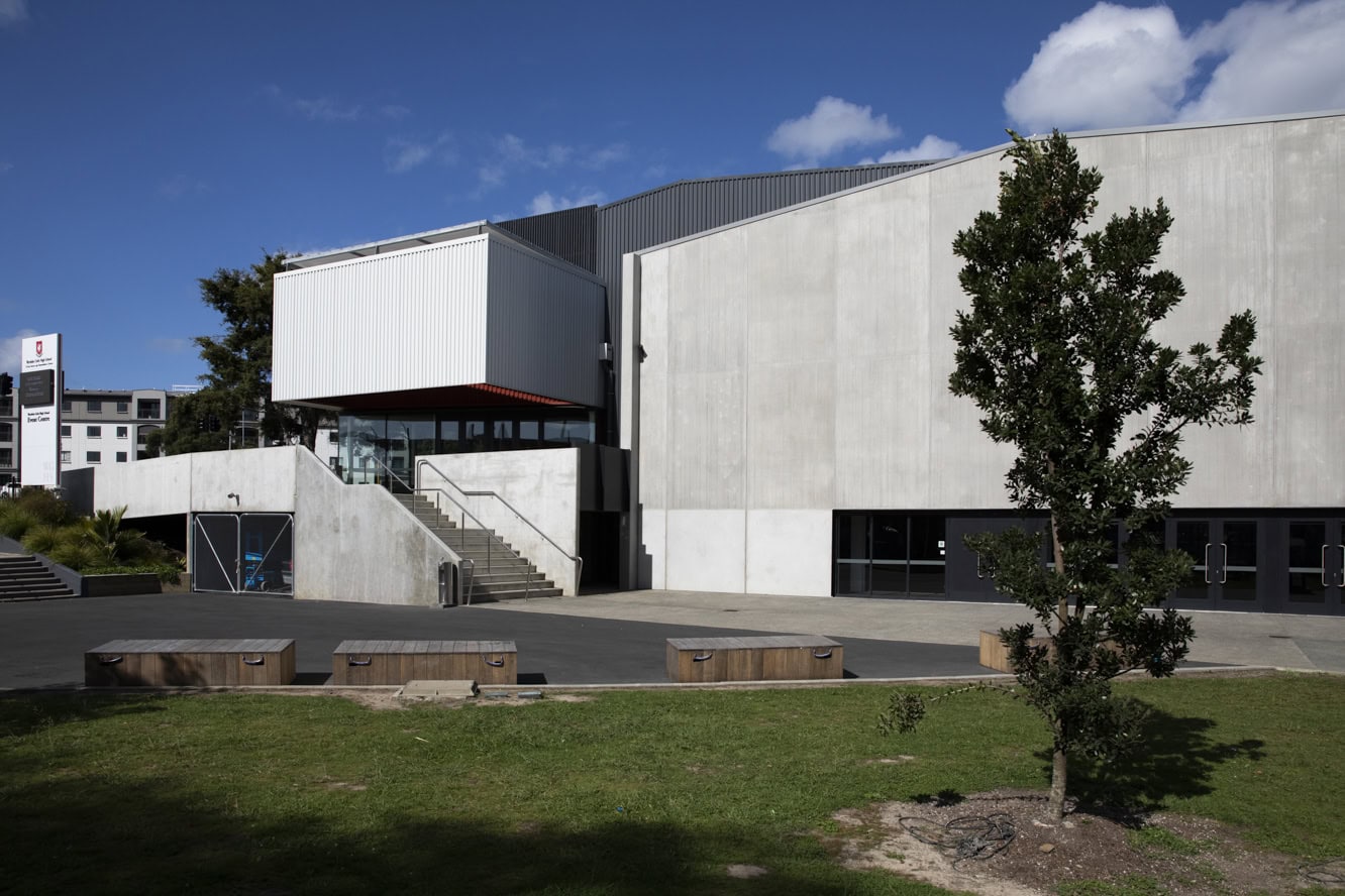 Large concrete and metal events building with external steps and timber seating, open grounds