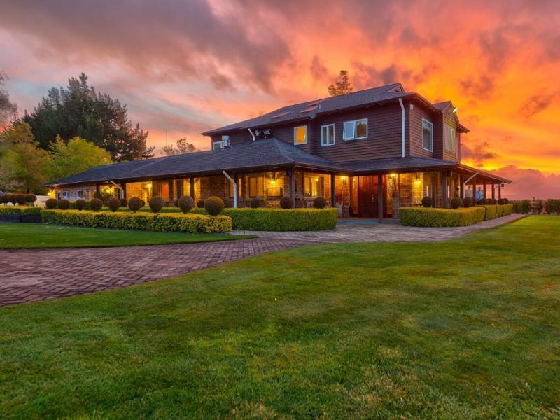 Timber homestead exterior at sunset with manicured lawn and topiary hedges