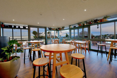 Dining and bar area with large windows, round tables and stools