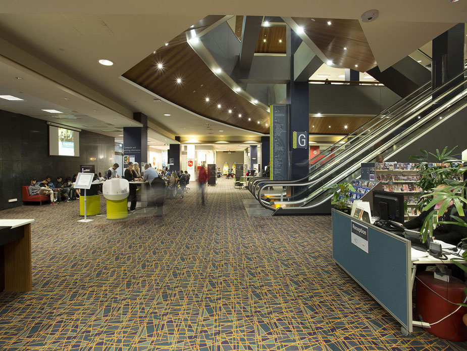 Library ground floor with escalator, reception desk and curved timber ceiling