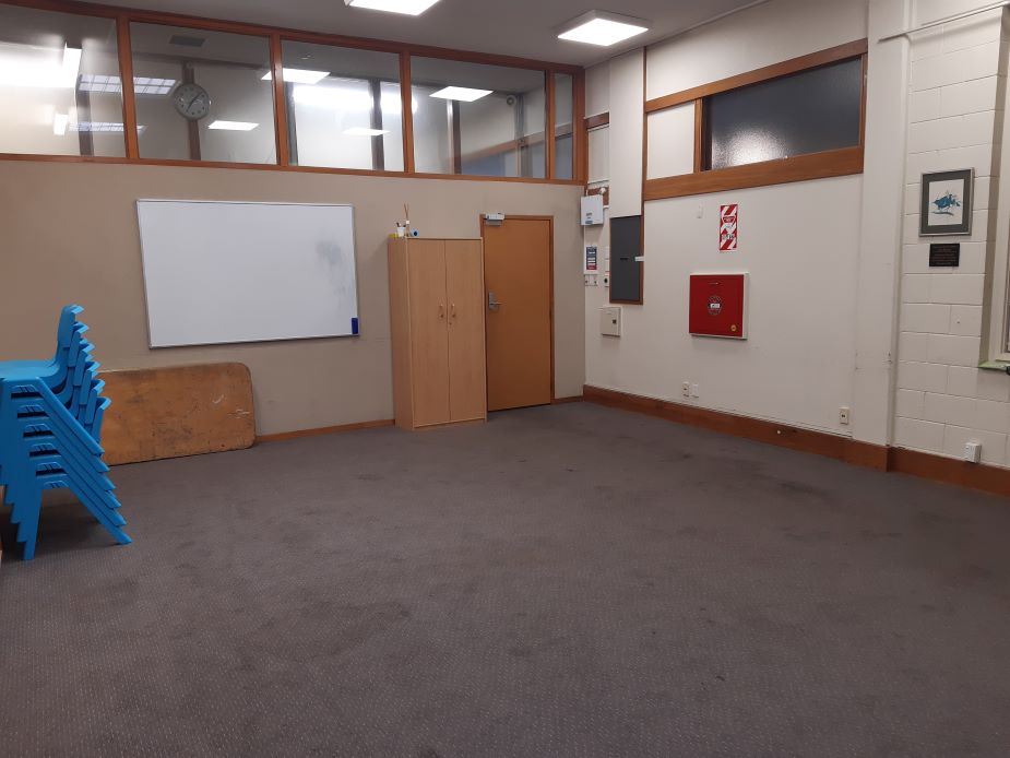 Empty carpeted room with blue chairs and whiteboard, different angle