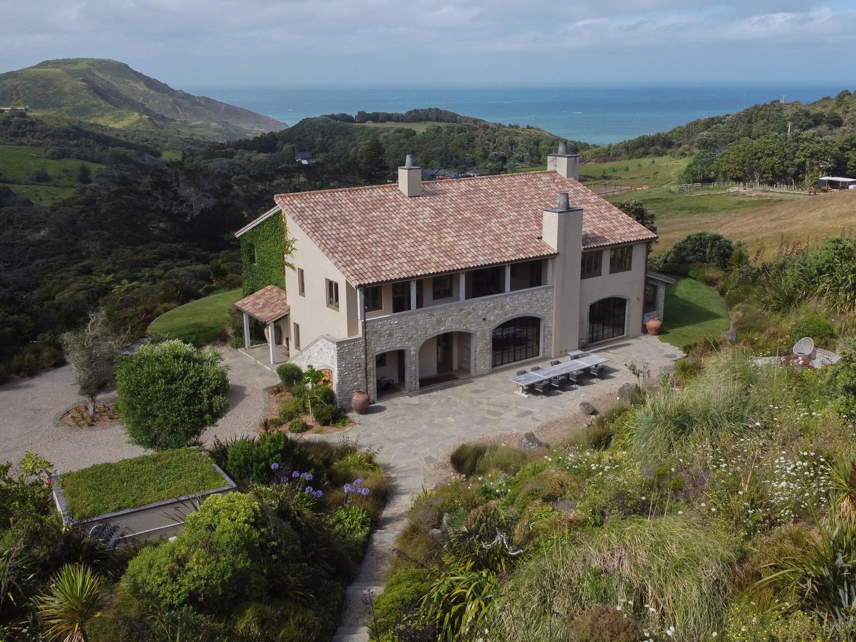 Aerial view of rendered stone estate building on coastal hillside