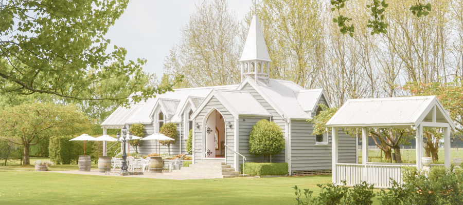 White chapel with steeple on manicured lawn with mature trees