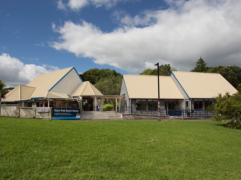 Single-storey community building with pointed metal roofs and a grass frontage