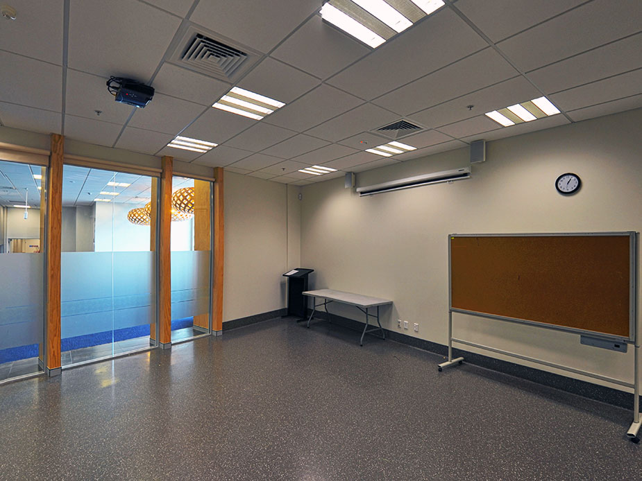 Plain meeting room with cork noticeboard, projector and glass partition wall