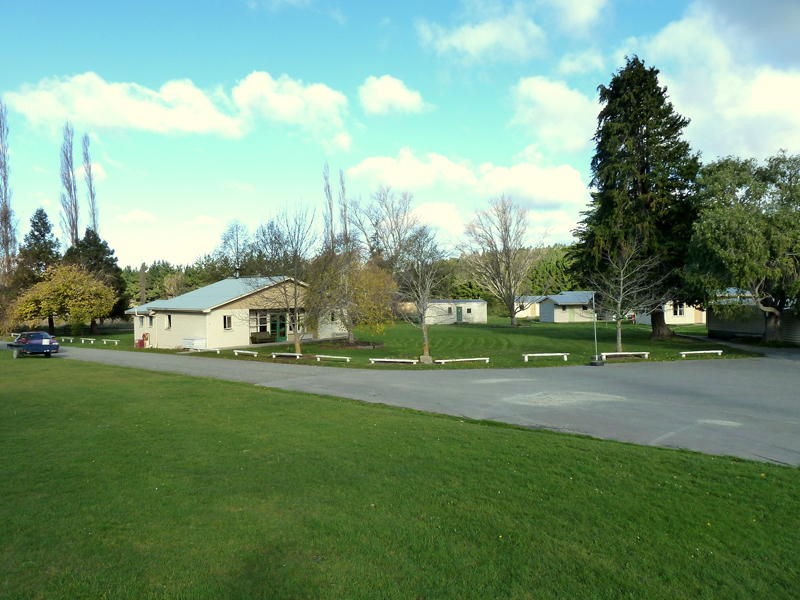 Camp grounds with low buildings, grass lawn and mature trees