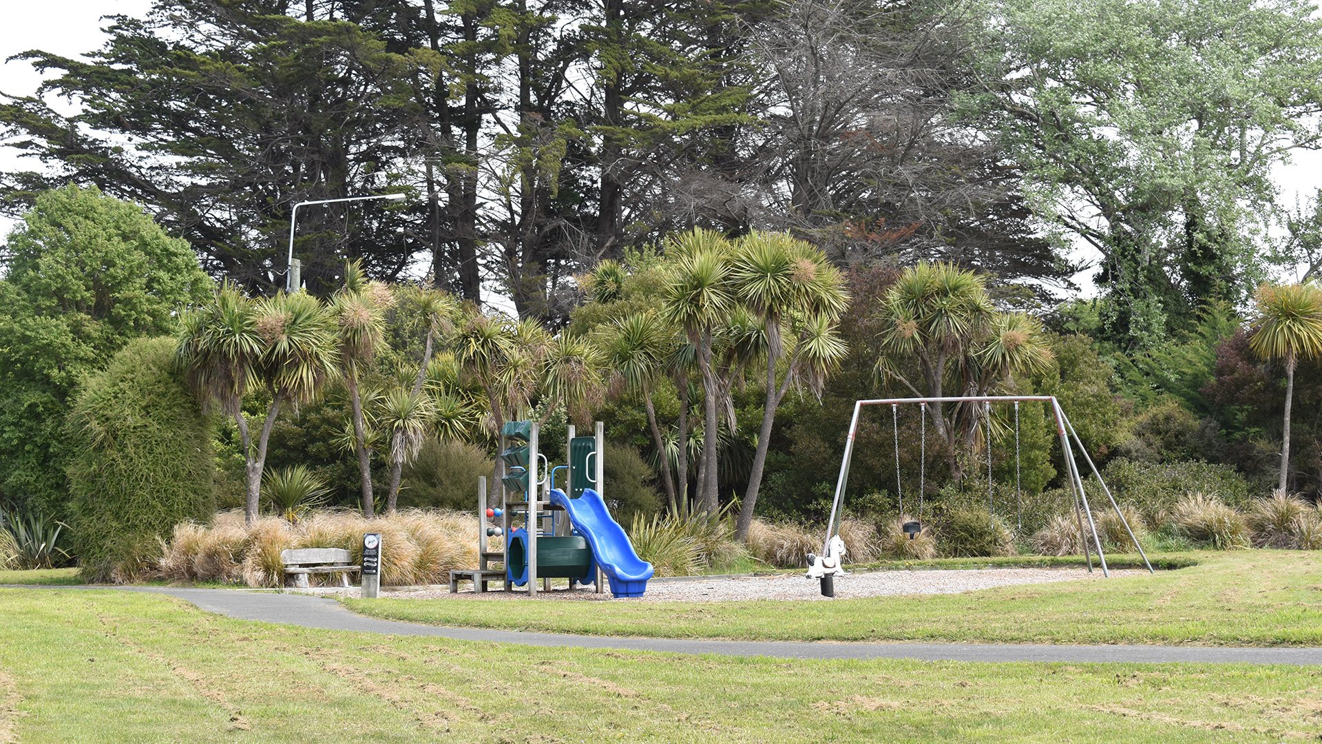Park playground with slide, swings and trees