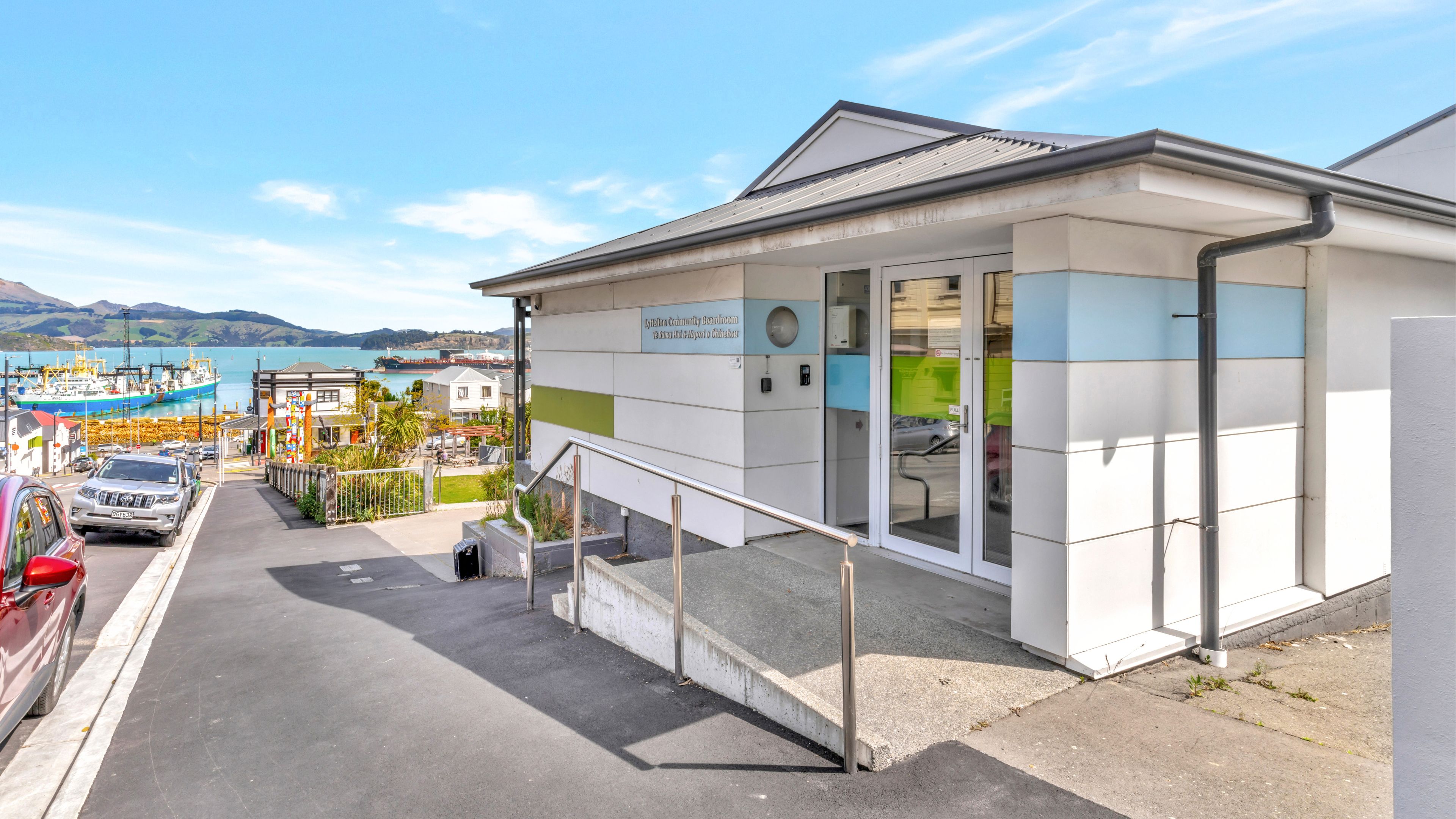 Modern white community building with harbour and hills in background