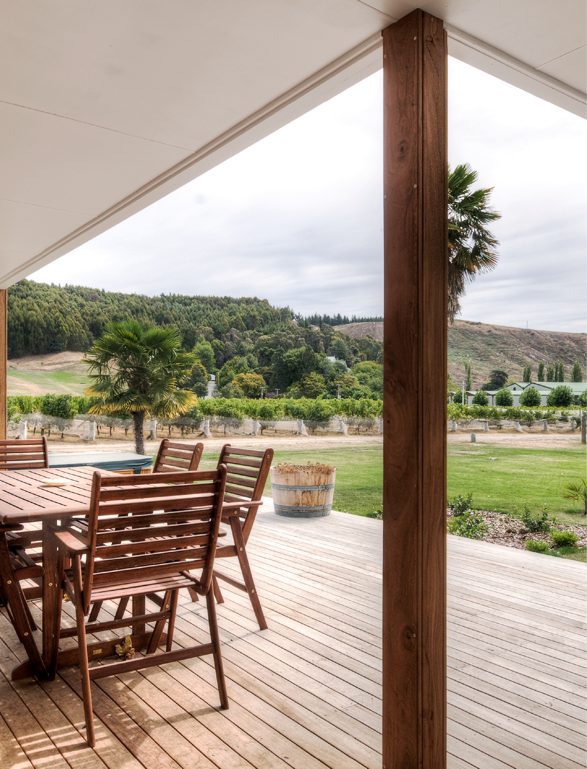 Covered timber deck with outdoor furniture overlooking vineyard rows and hills