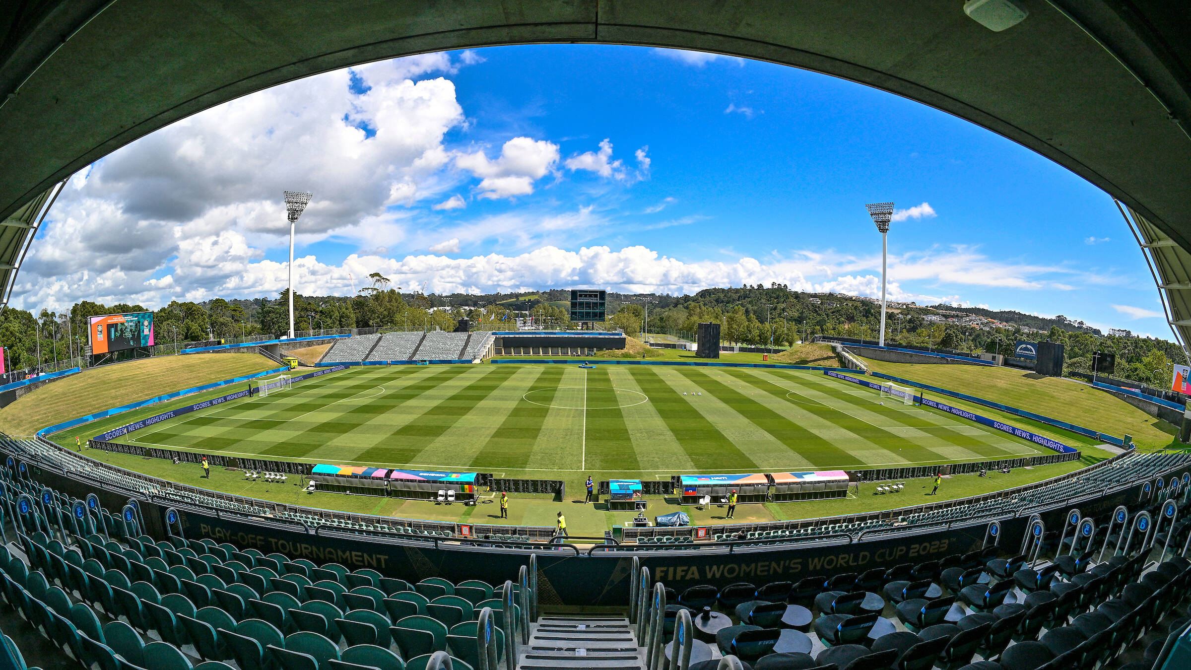 Empty stadium bowl with grass pitch and covered grandstands viewed from end