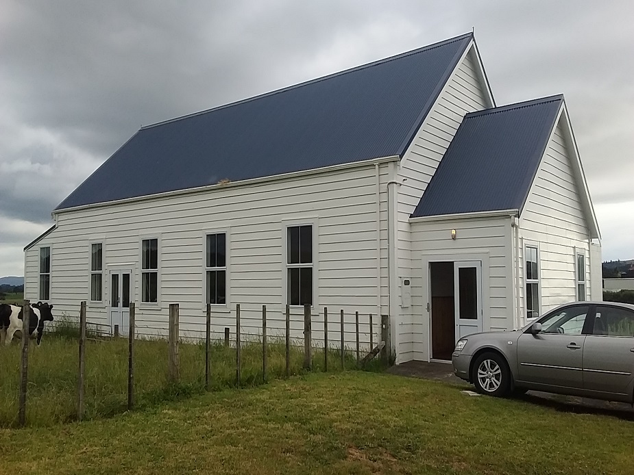 White weatherboard hall with blue iron roof, set in rural paddock