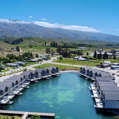 Aerial view of lakeside resort with rows of cabins and marina, mountains behind