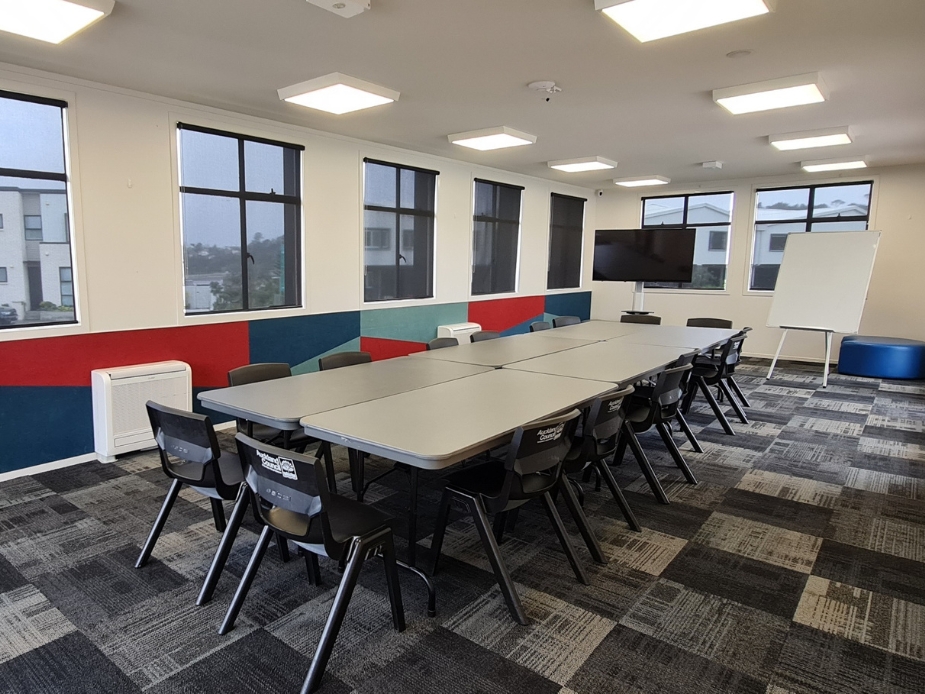 Meeting room with long table, chairs, screen, and whiteboard
