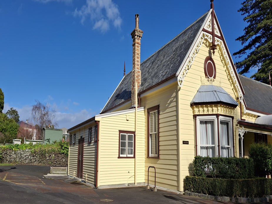 Side and rear view of yellow Victorian weatherboard building with bay window