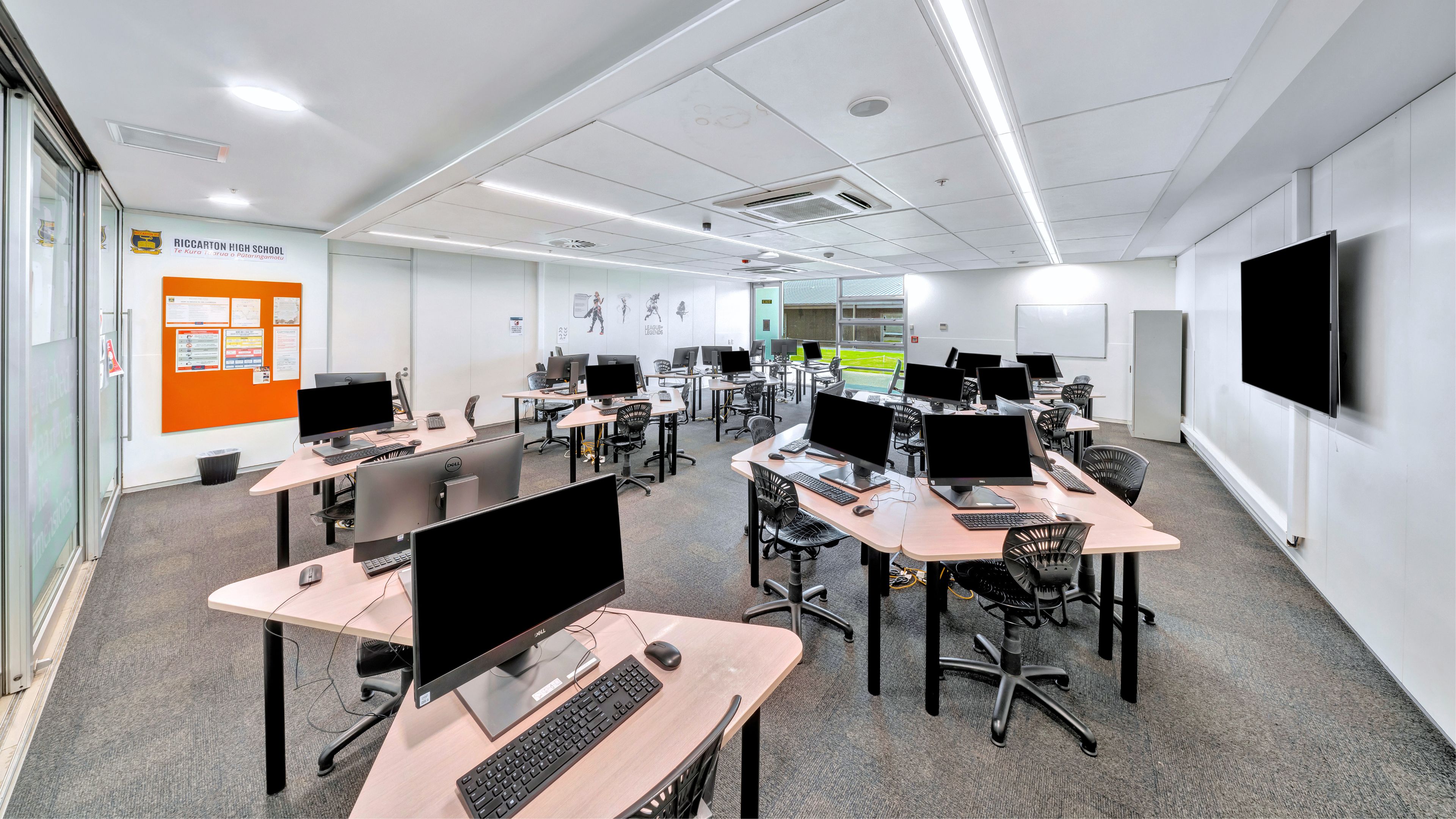 Computer classroom with desktop workstations and wall-mounted screen