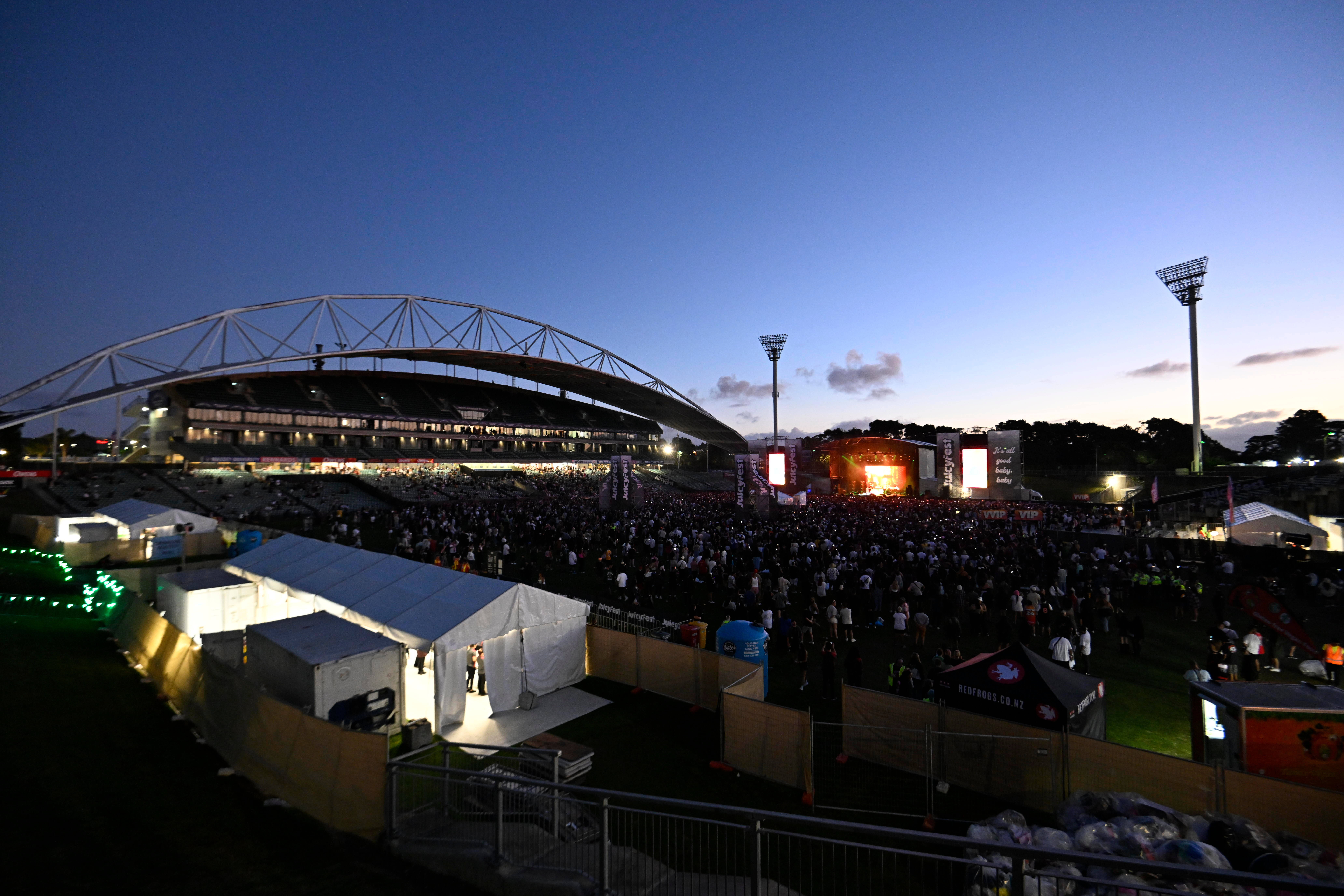 Stadium exterior at dusk with concert event and large crowd on field