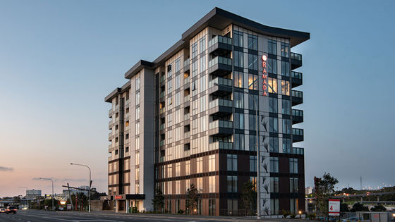 Multi-storey hotel building with glazed facade lit at dusk on city street