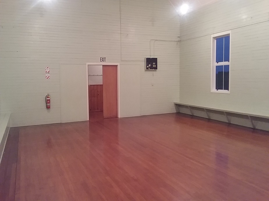 Empty white hall interior with polished timber floor and wall bench seating