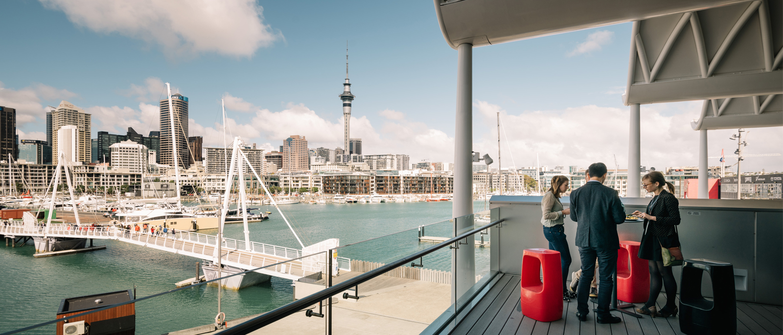 Open balcony deck overlooking harbour with city skyline and sky tower in background