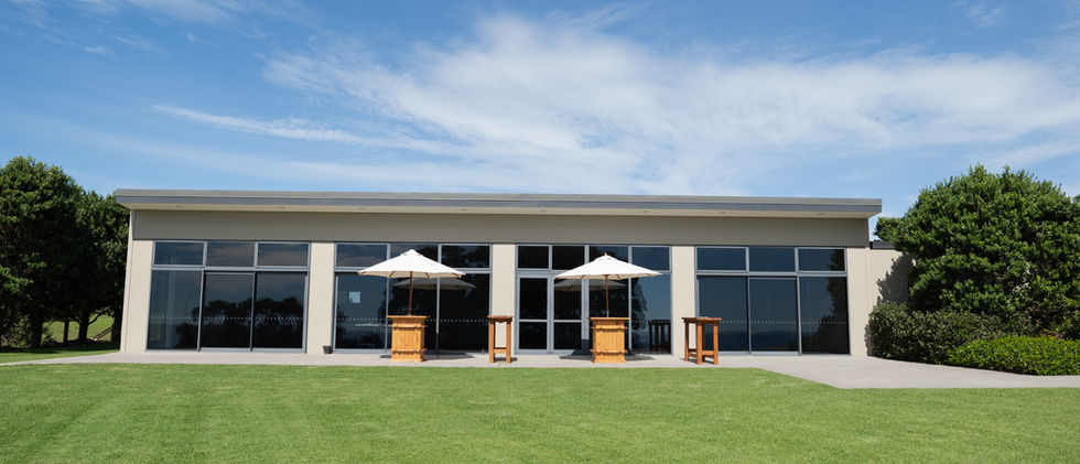 Single-storey venue building with full-height glazing and lawn in front