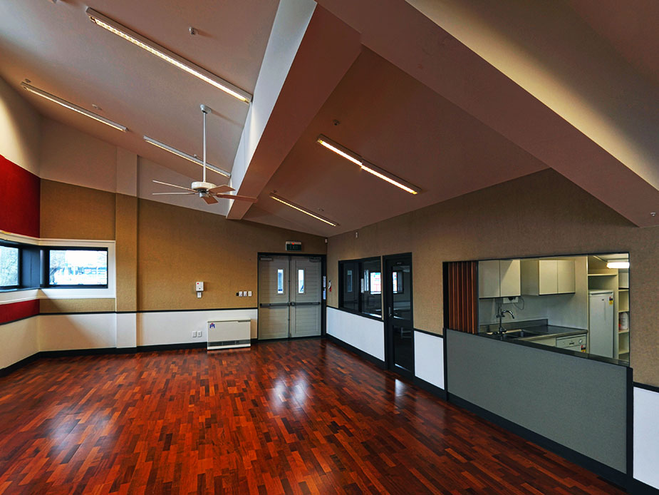 Function room with vaulted ceiling, polished timber floor, and kitchen servery hatch