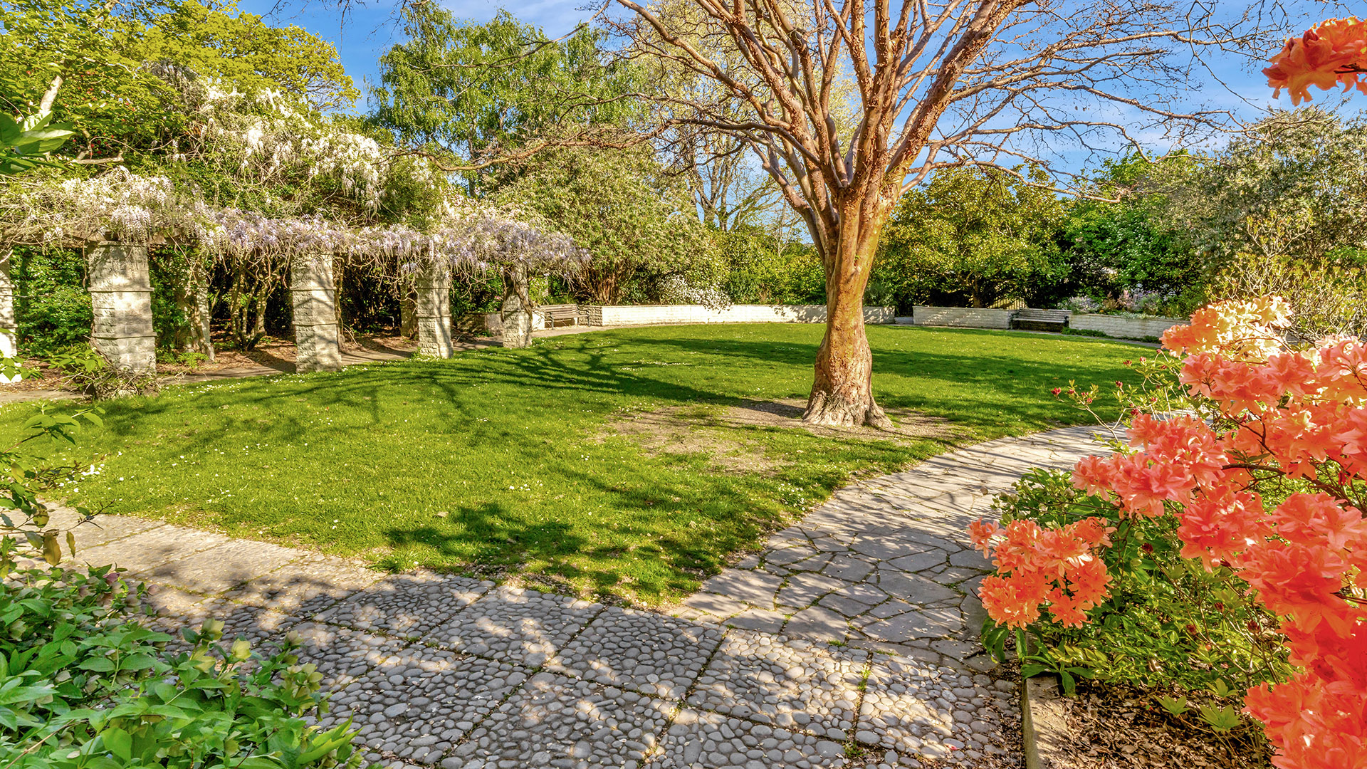 Formal garden with stone pergola, lawn, and flowering plants