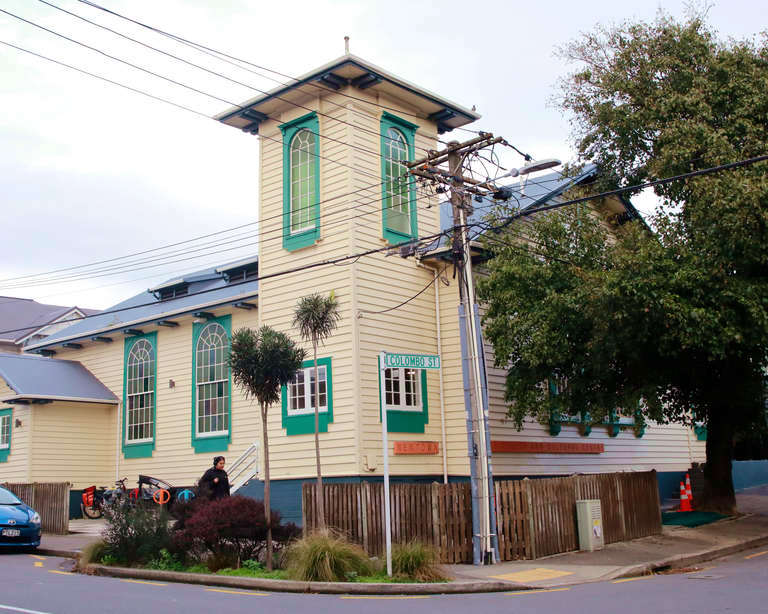 Two-storey timber church building painted cream and teal with corner tower