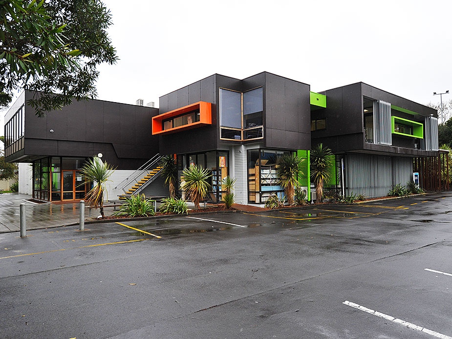 Contemporary dark-cladded two-storey building with bold orange and green accents