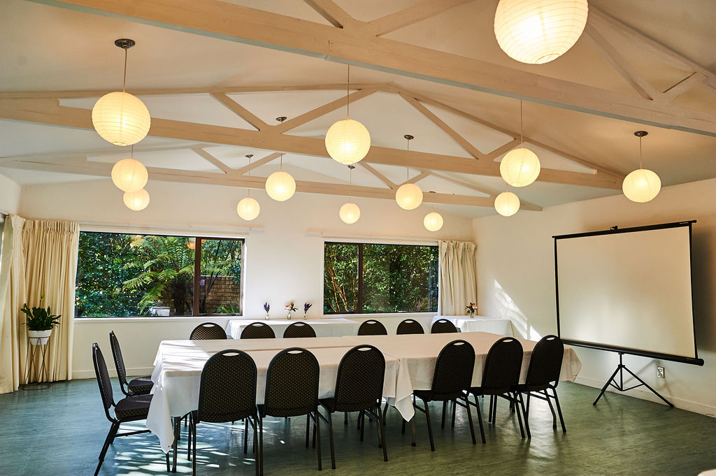 Bright meeting room with vaulted timber ceiling, globe pendant lights, long table and projection screen