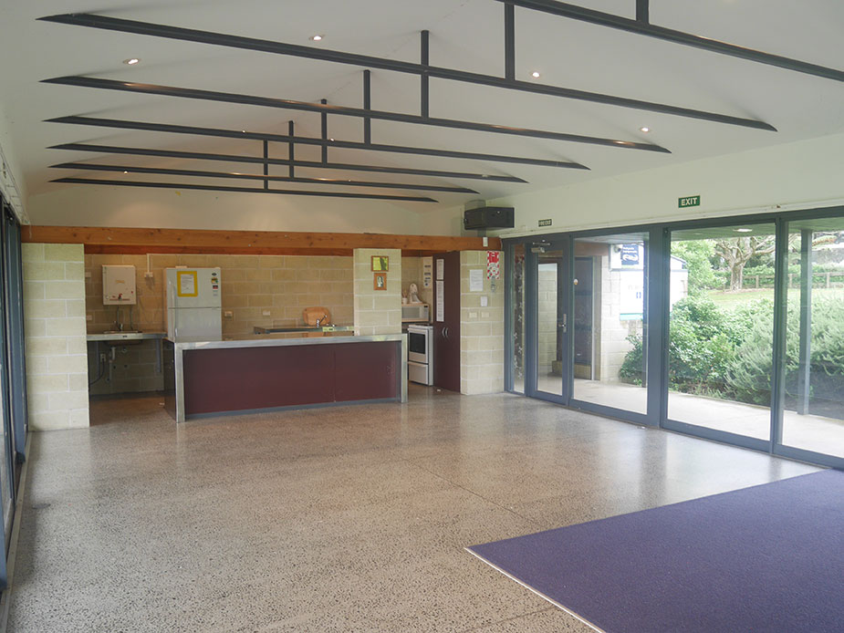 Open hall interior with polished concrete floor, kitchen servery and glass doors