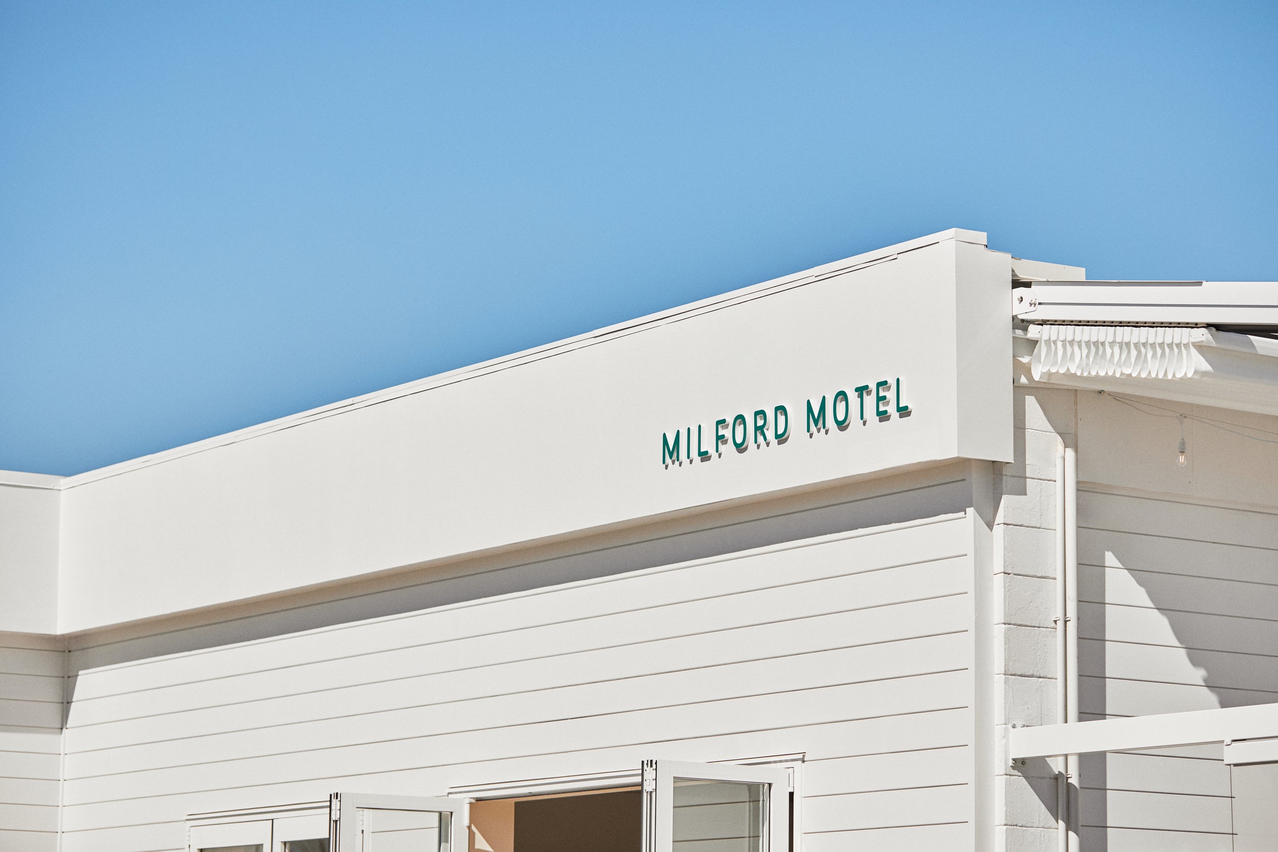 White motel building facade with signage under blue sky