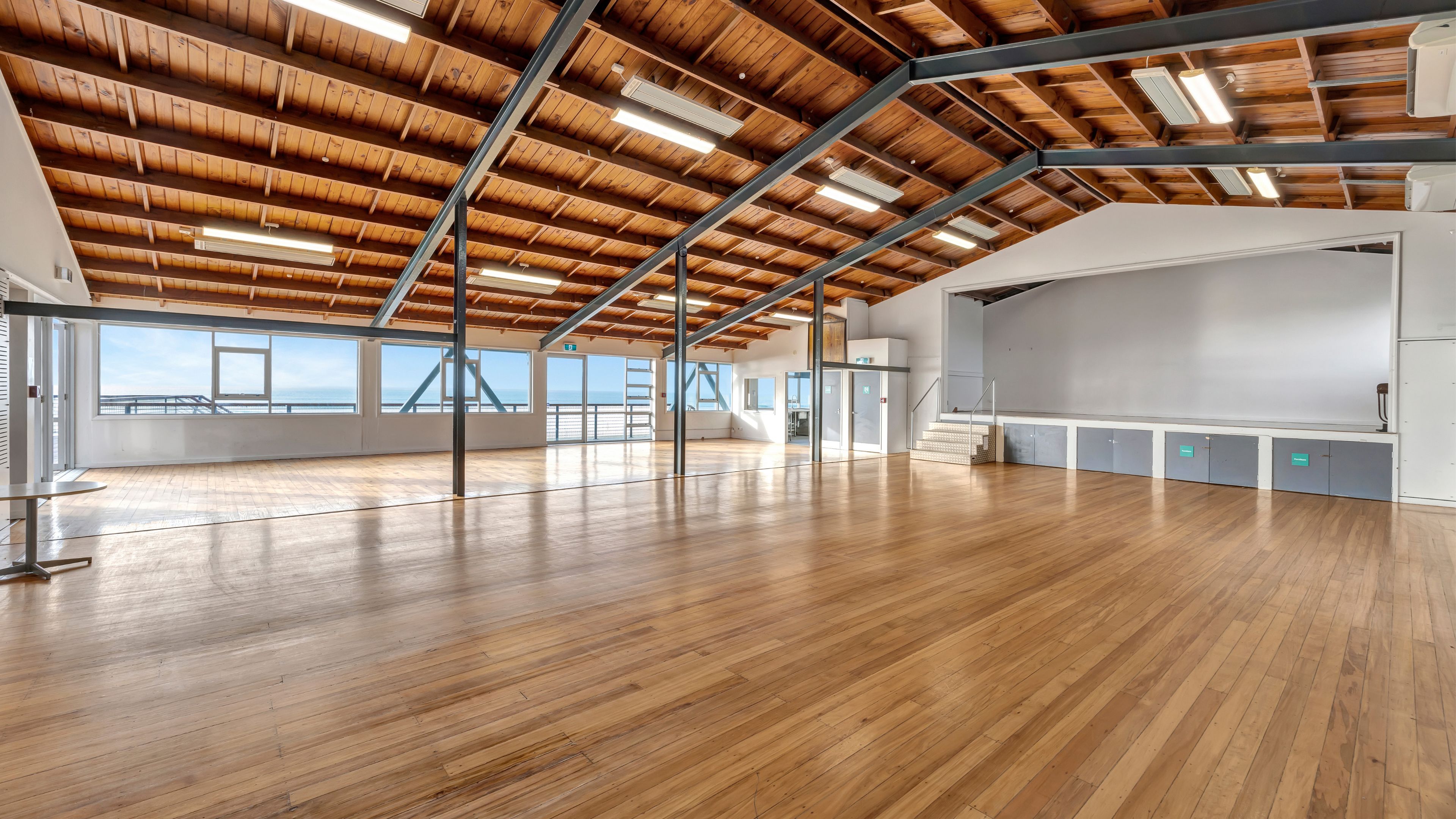 Large open hall with timber ceiling, exposed steel beams and polished wood floors