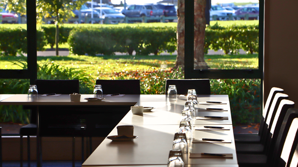Conference room with boardroom table set for a meeting, garden views through windows