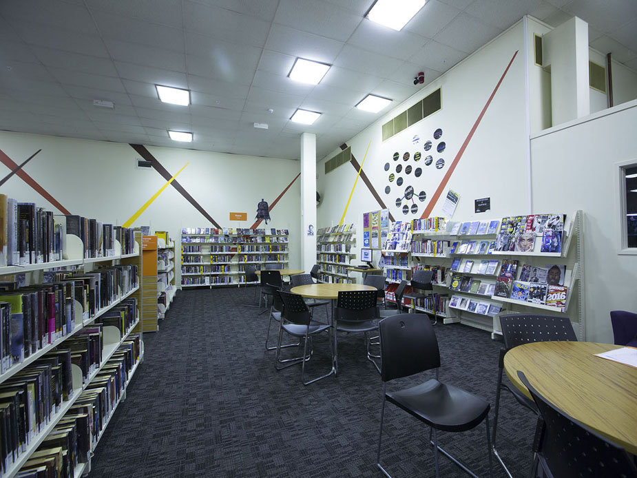 Library interior with book shelves, display stands, and decorated walls