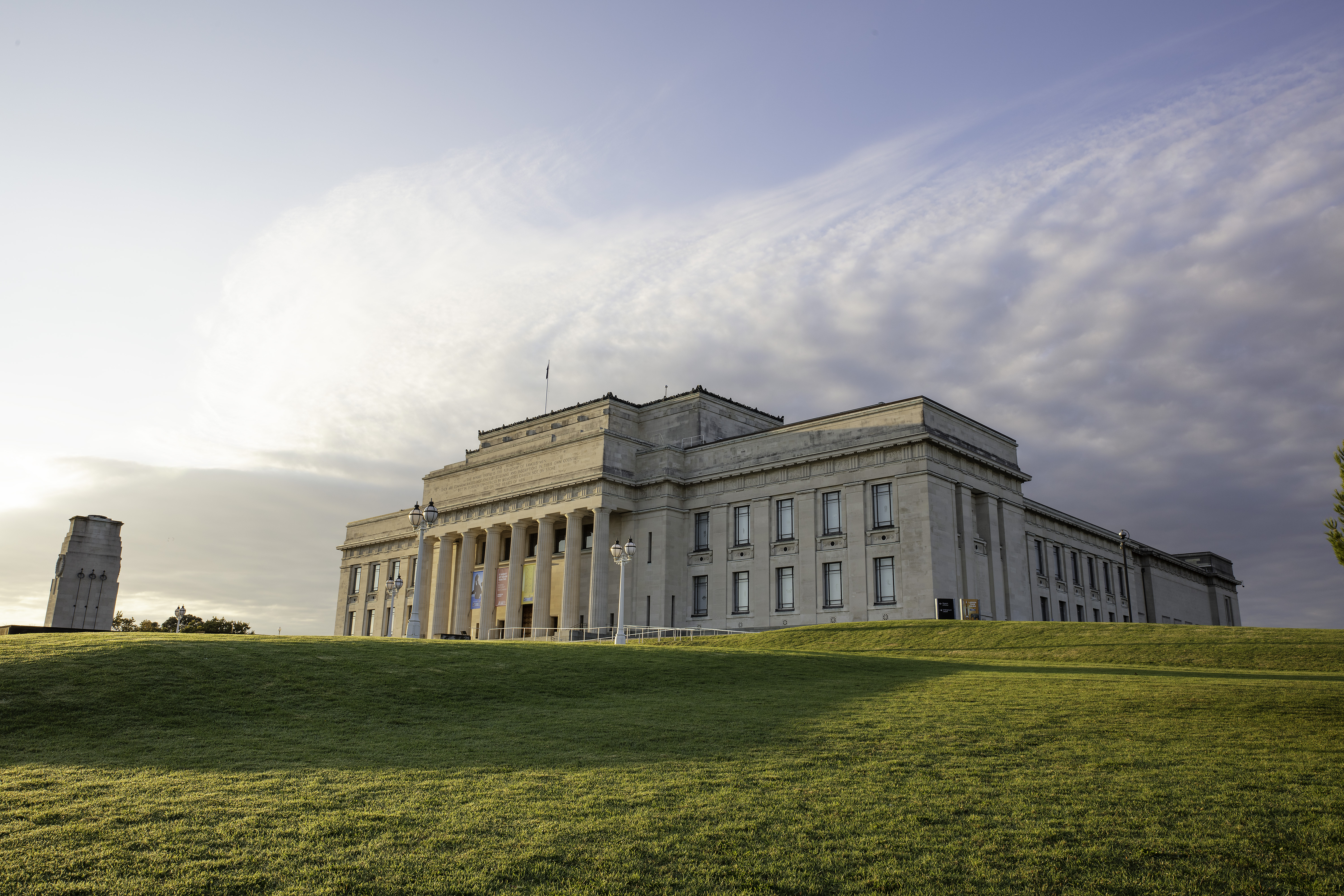 Classical stone museum building on open grass field