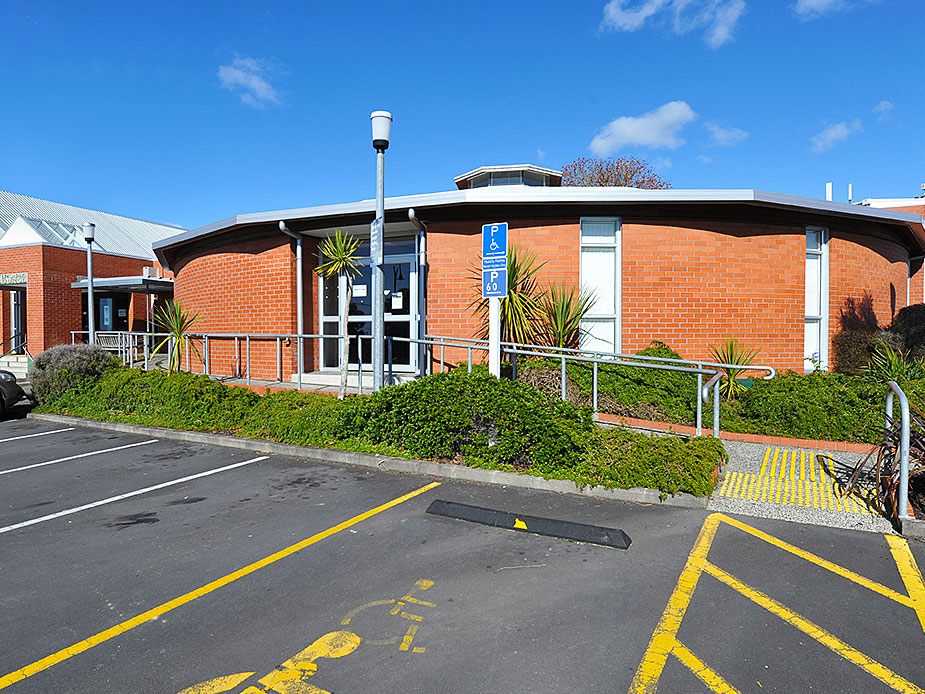 Curved brick library building with car park and blue sky
