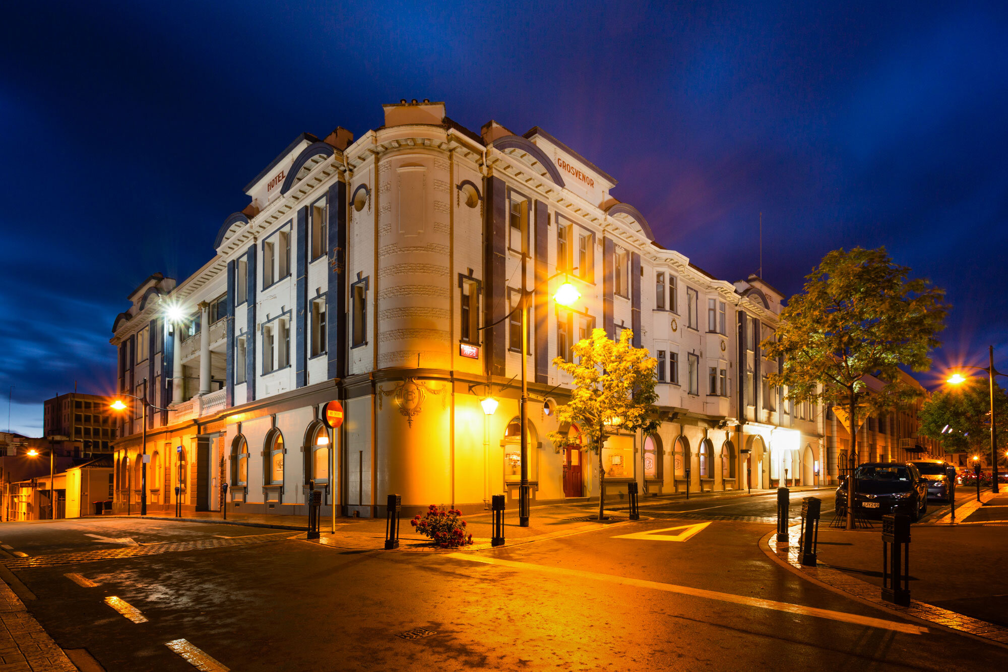 White heritage corner building with arched windows and ornate parapet, lit at night