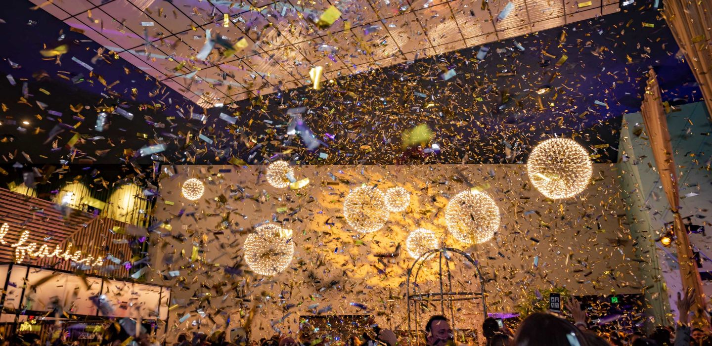 Indoor event space filled with falling confetti, spherical pendant lights and warm uplighting