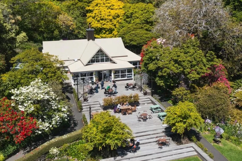 Aerial view of venue building and deck surrounded by mature garden trees