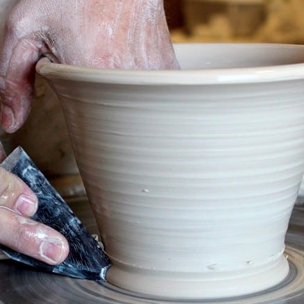 Hands shaping clay on a pottery wheel