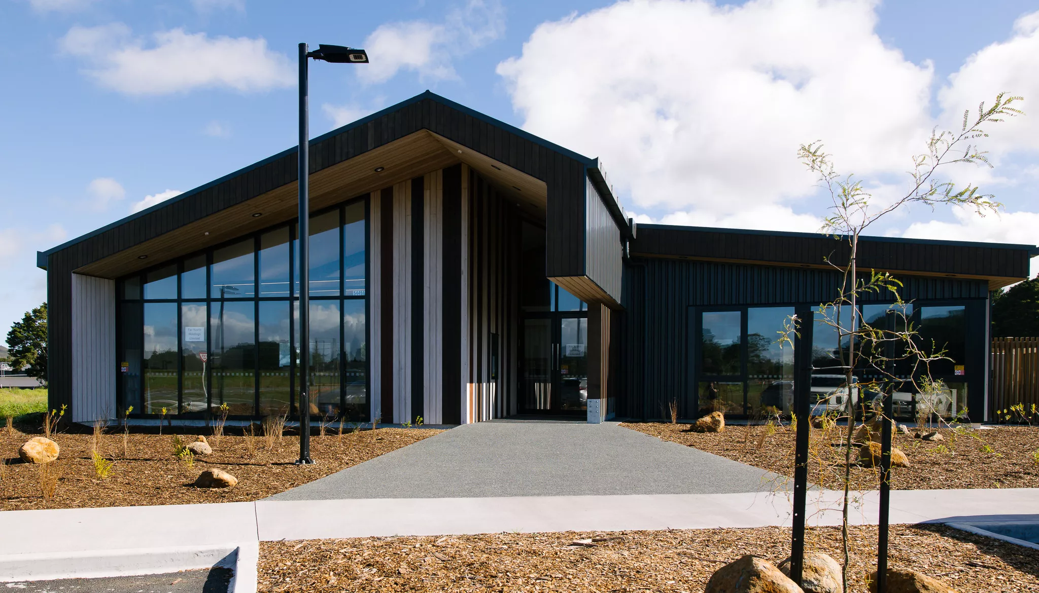 Single-storey dark-clad building with large glazed entry and timber accents