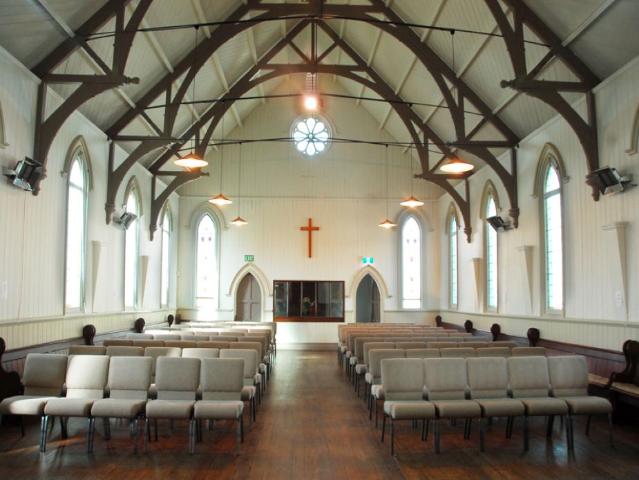 Church nave interior with arched ceiling, timber trusses and pews