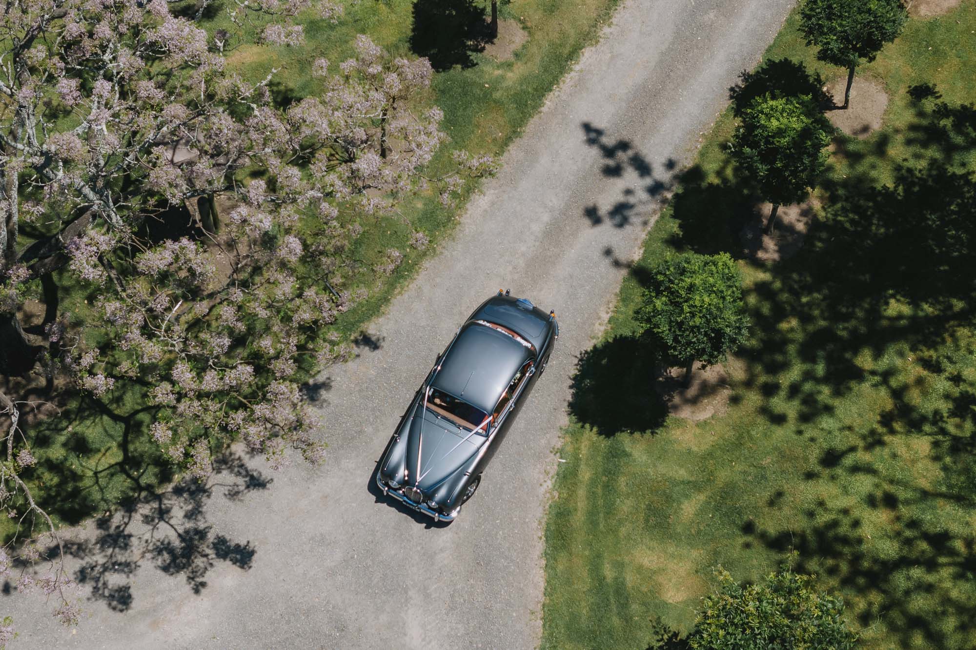 Aerial view of classic car on gravel drive through venue grounds